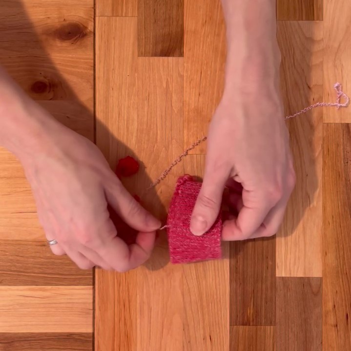 Étape 1 pour le détricot: une main tient le morceau à détricoter et l'autre le fil 