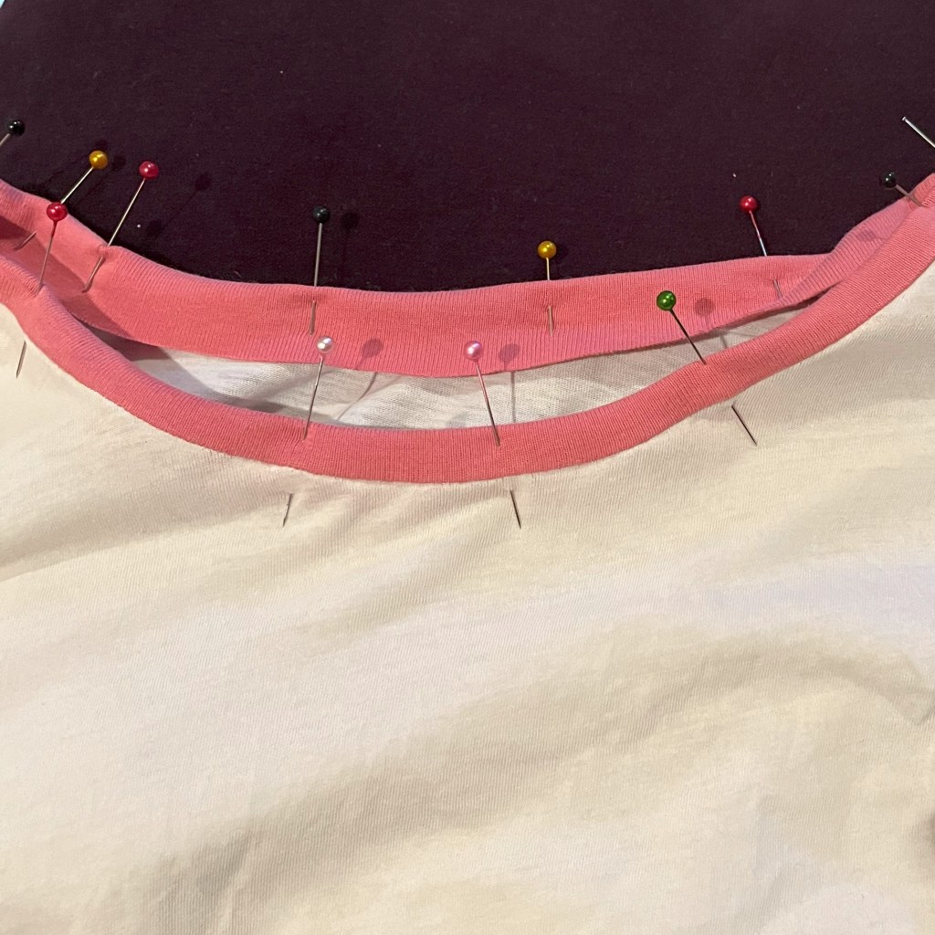 Une bande de couleur est repliée et épinglée sur le col d'un t-shirt