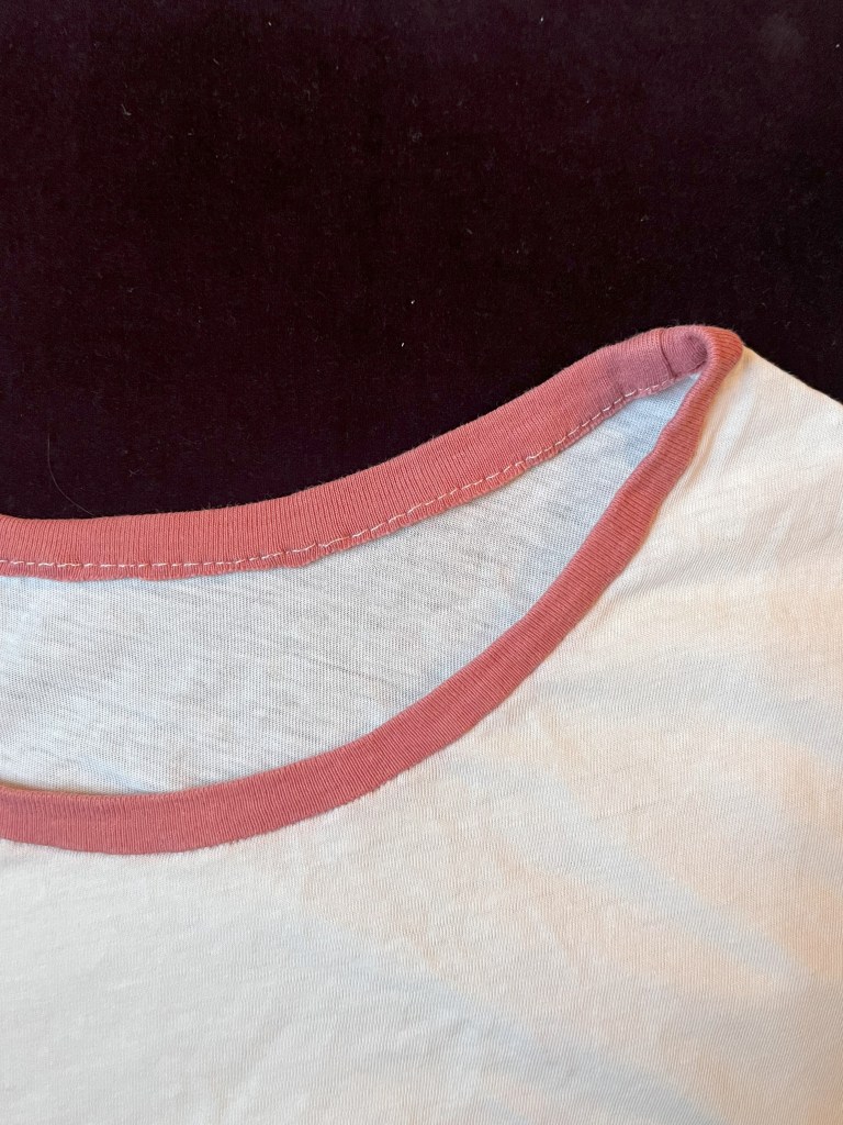 Col de t-shirt rose neuf sur t-shirt usagé blanc, cousu à la machine à coudre