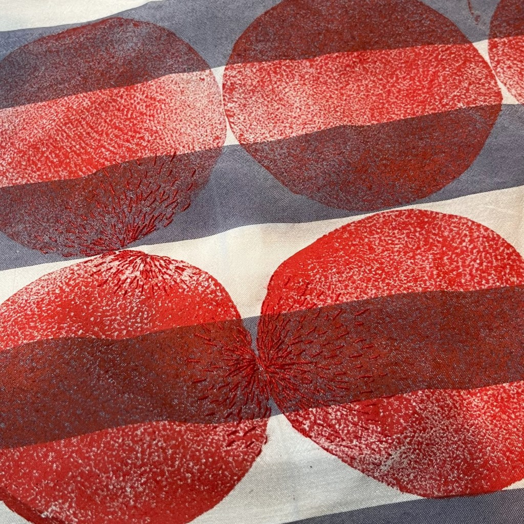 cercles rouges imprimés sur un tissus à rayures avec de la broderie